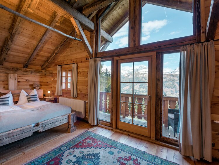 Schlafzimmer mit Holzbett und Aussicht auf die Berge einer Premiumhütte | © Günter Standl 