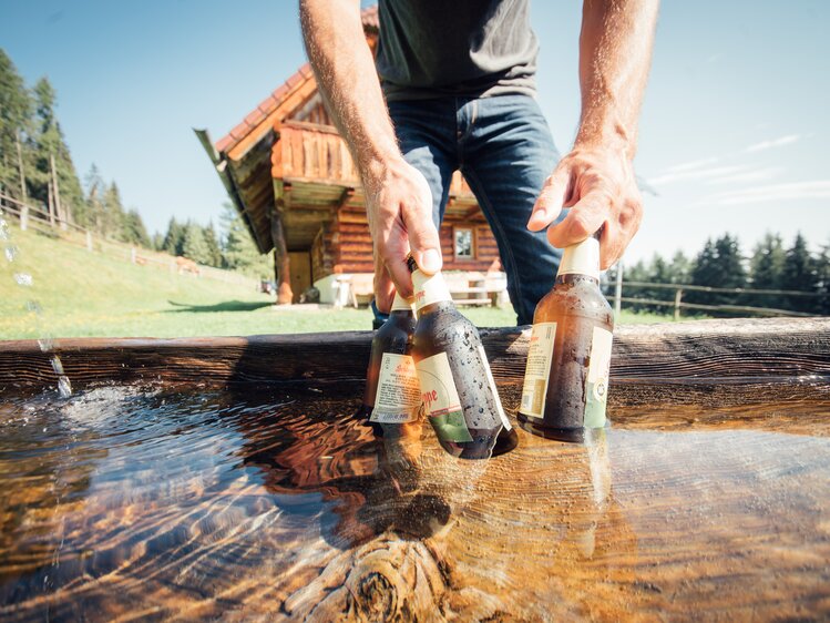 Mann holt gekühlte Getränke aus dem Brunnenwasser | © Urlaub am Bauernhof Steiermark / Daniel Gollner 