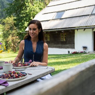 Cooking Catrin mit Himbeerdessert und Almhütte im Hintergrund | © Carletto Photography / Urlaub am Bauernhof Kärnten