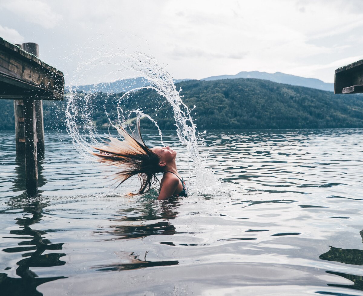 Mädchen im See spritzt das Wasser mit den Haaren | © Urlaub am Bauernhof Kärnten/ Daniel Gollner