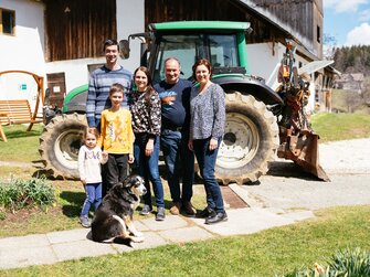 Die Familie steht vor einem Traktor | © Urlaub am Bauernhof Kärnten / Daniel Gollner