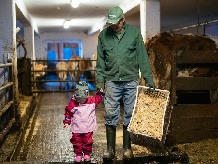 Kind steht mit Mann im Stall | © Urlaub am Bauernhof Kärnten / Daniel Gollner