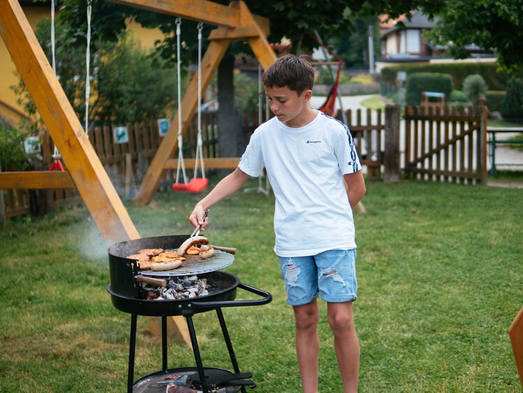 Bub hilft fleißig am Kugelgrill mit | © Urlaub am Bauernhof / Daniel Gollner