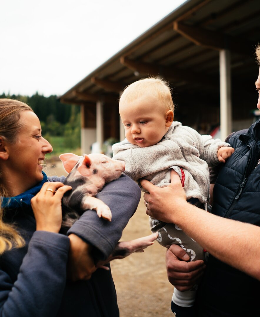 Familie mit Babyschwein in der Hand | © Urlaub am Bauernhof Kärnten/ Daniel Gollner