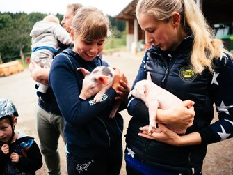 Frau und Mädchen halten die Babyschweine | © Urlaub am Bauernhof Kärnten/ Daniel Gollner