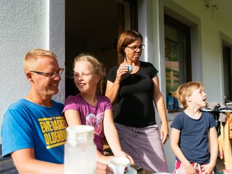 Familie sitzt vor dem Haus auf der Bank | © Urlaub am Bauernhof Kärnten / Daniel Gollner