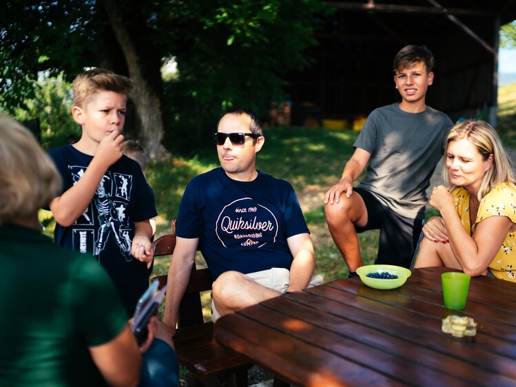 Familie sitzt am Tisch und Buben stehen daneben | © Urlaub am Bauernhof Kärnten / Daniel Gollner