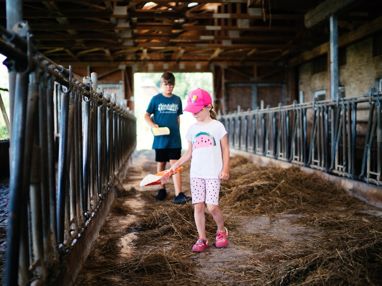 Kinder verteilen das Futter im Stall | © Urlaub am Bauernhof Kärnten / Daniel Gollner