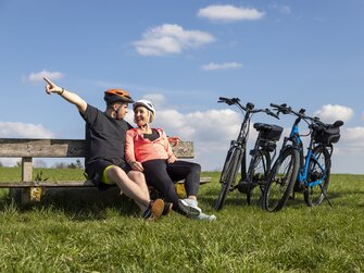 Paar macht bei einer E-Bike-Tour Rast auf einer Bank | © Urlaub am Bauernhof Oberösterreich / Puremotions Photography