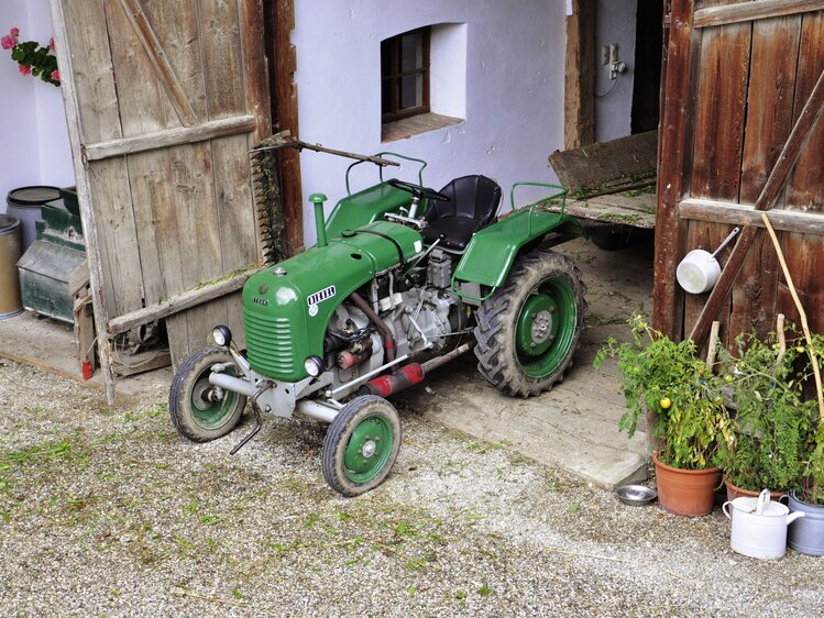 Grüner Oldtimer-Traktor steht im Stadl | © Urlaub am Bauernhof Oberösterreich / Harald Puchegger