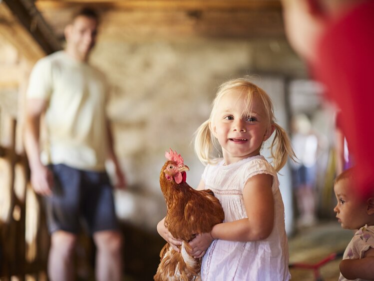 Mädchen hält ein Huhn auf dem Arm | © Urlaub am Bauernhof Oberösterreich / Alexander Kaiser