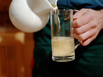 Bauer schenkt ein Glas selbstgemachten Most ein