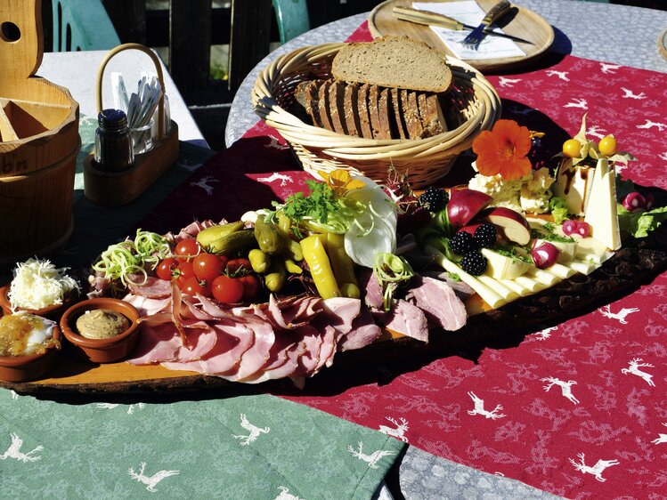 Reichlich verzierte Brettljause mit Käse, Fleisch, Gemüse, Blüten, Kräutern und Bauernbrot | © Urlaub am Bauernhof Oberösterreich / Harald Puchegger