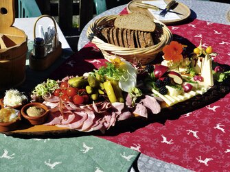 Reichlich verzierte Brettljause mit Käse, Fleisch, Gemüse, Blüten, Kräutern und Bauernbrot | © Urlaub am Bauernhof Oberösterreich / Harald Puchegger