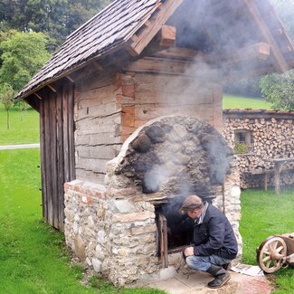 Bauer heizt das traditionelle Dörrhäusl zum Obst dörren ein | © Urlaub am Bauernhof Oberösterreich / Harald Puchegger