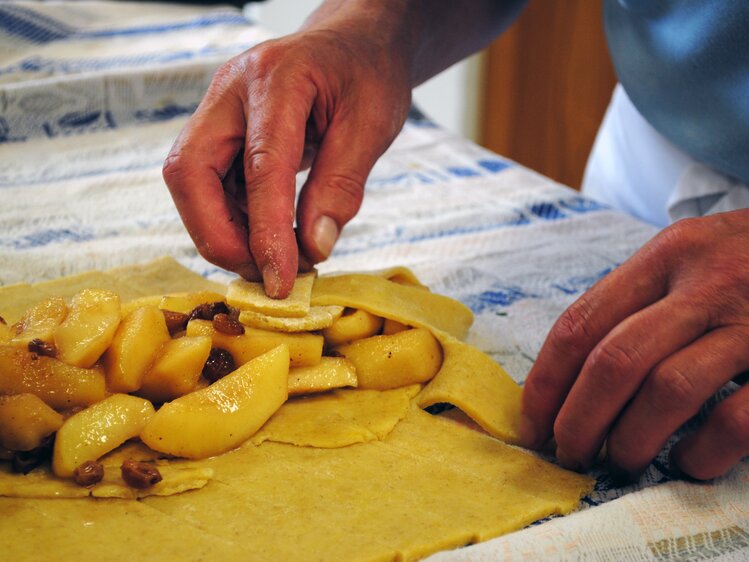 Die Bäuerin schlägt den Teig über der Fülle des Apfelstrudels ein. | © Urlaub am Bauernhof Oberösterreich / Manuela Edlbauer