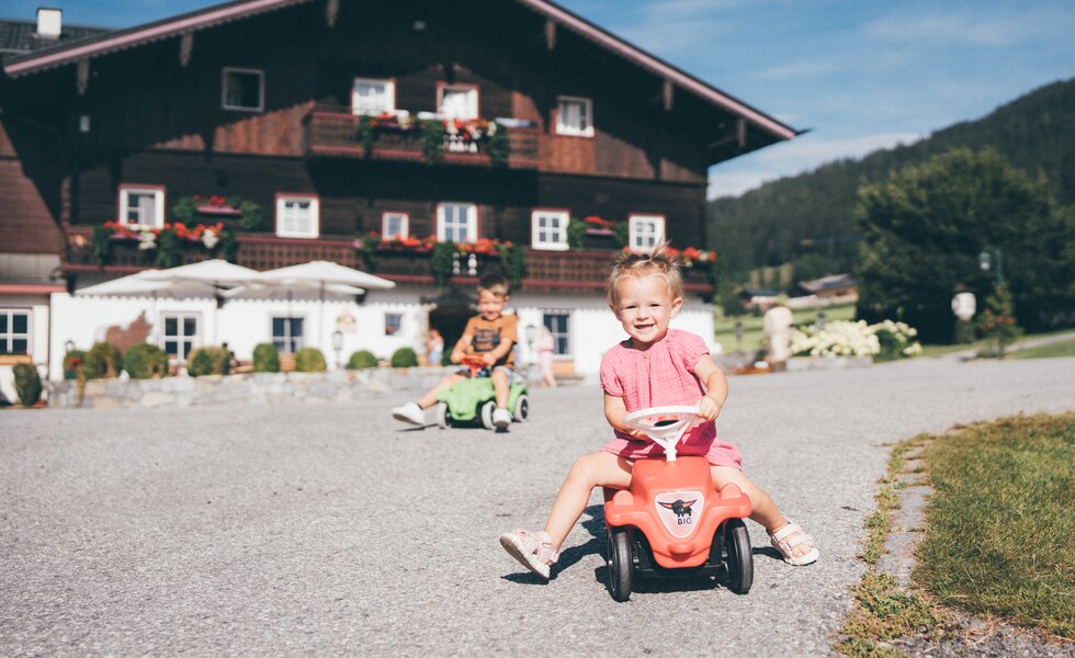 Maedchen und Bub fahren mit Bobbycar | © Urlaub am Bauernhof / Daniel Gollner