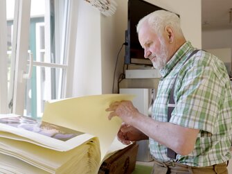 Altbauer Josef schmökert in alten Fotos | © Daniel Gollner / Urlaub am Bauernhof