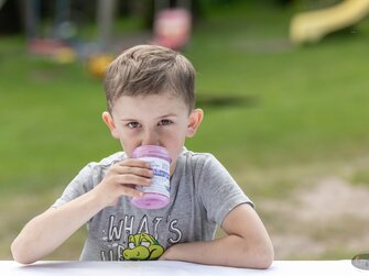 Bub sitzt auf einer Bank und genießt sein Heidelbeerjoghurt | © Bio-Bergbauernhof Weger