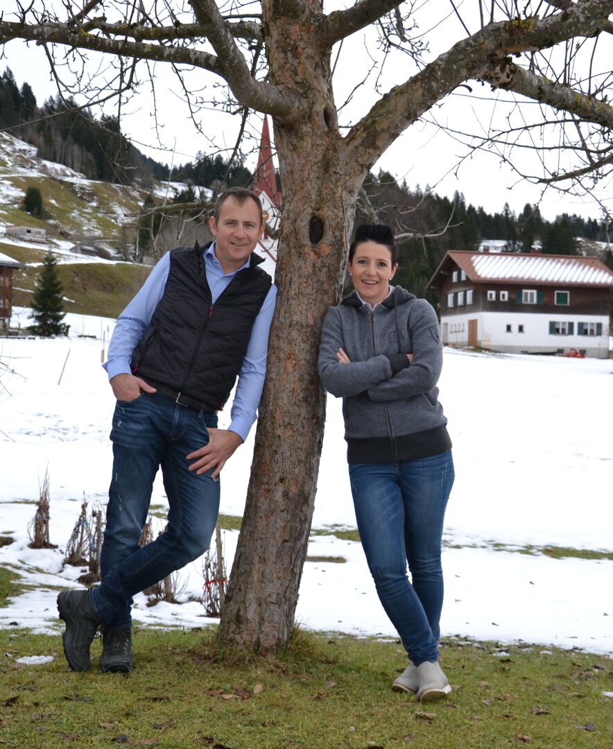 Bauer und Baeuerin lehnen am Baum vor verschneiter Wiese | © Urlaub am Bauernhof Österreich / Dorner