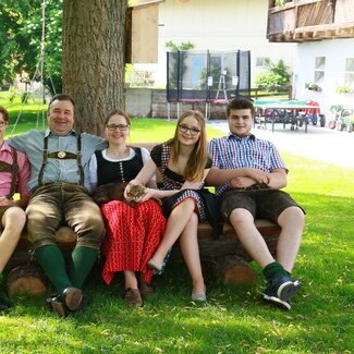 Familie Kerschbaumer sitzt auf Holzbank im Garten am Hönigshof | © Urlaub am Bauernhof Österreich / Wolfgang Baumgartner