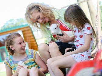 Bäuerin mit 2 Mädchen und Kitz im Freien | © Urlaub am Bauernhof Österreich / Kerndler 