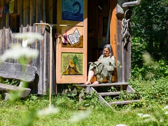 Frau sitzt auf Stufen vor einer Hütte | © Urlaub am Bauernhof