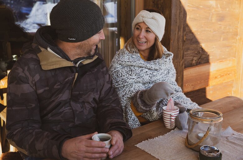 Paar sitzt auf Hausbank und trinkt Tee im Winter | © Urlaub am Bauernhof / Pascal Baronit