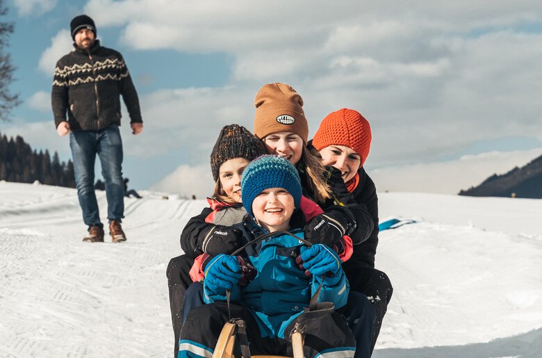 Eine Familie sitzt auf einem Schlitten | © Urlaub am Bauernhof / Punkt und Komma