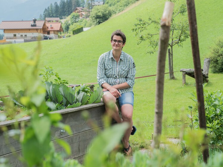 Gastgeberin Barbara Lainer sitzt auf ihrem Hochbeet. | © Urlaub am Bauernhof im SalzburgerLand / Matthias Gruber