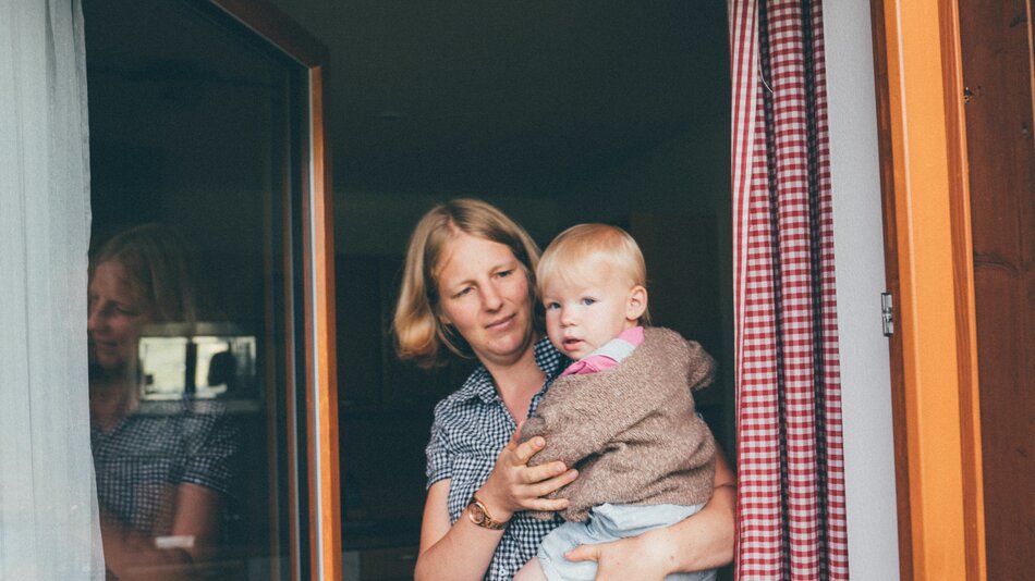 Bäuerin Kathrin Röck vom Grußberggut in Bad Hofgastein hält ihr Baby am Arm | © Urlaub am Bauernhof im SalzburgerLand / Daniel Gollner