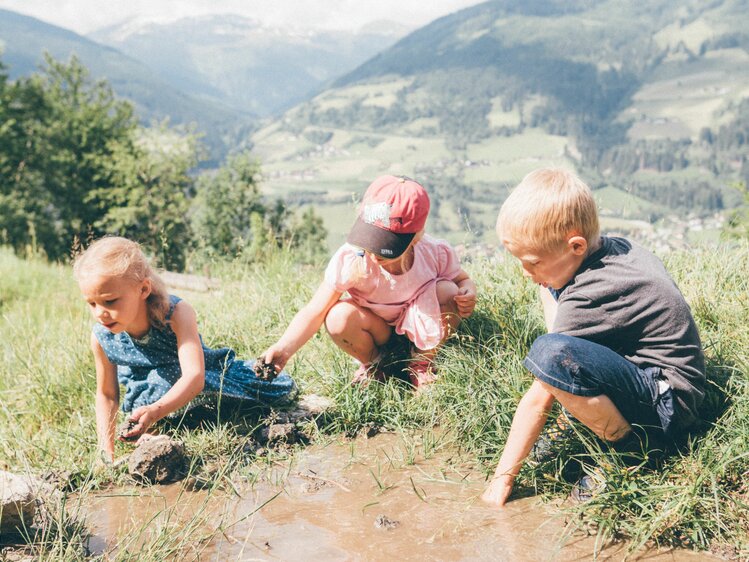 Drei Kinder spielen auf der Alm vom Grußberggut in Bad Hofgastein mit Wasser | © Urlaub am Bauernhof im SalzburgerLand / Daniel Gollner