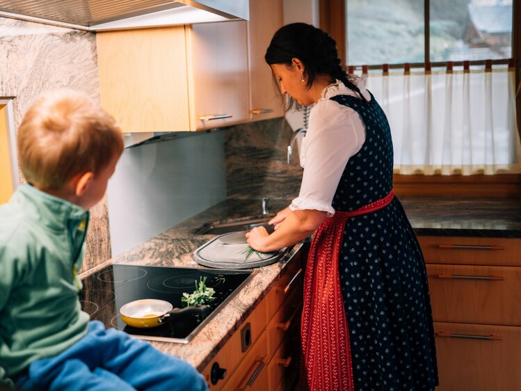 Bäuerin kocht, schneidet Schnittlauch, Bub schaut ihr zu. Maurachhof in St. Johann, Salzburger Land | © Urlaub am Bauernhof Salzburger Land / Daniel Gollner