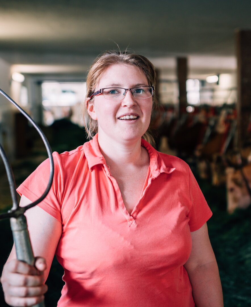 Bäuerin Maria Höpflinger steht in ihrem Stall und hat die Heugabel in der Hand. | © Urlaub am Bauernhof im SalzburgerLand / Daniel Gollner