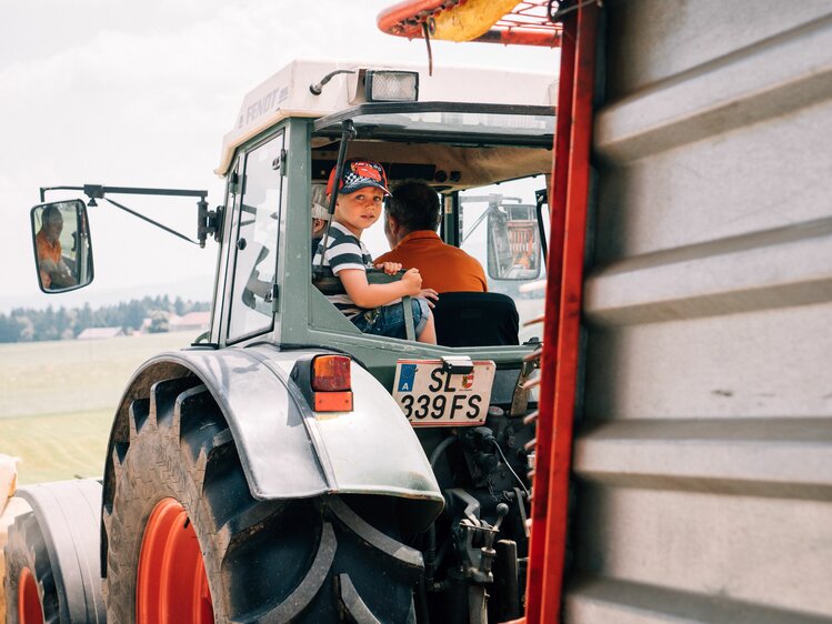 Bub darf mit dem Bauern am Traktor mitfahren. | © Urlaub am Bauernhof im SalzburgerLand / Daniel Gollner