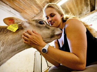 Frau streichelt ein Kalb im Stall, Urlaubsregion Murau-Murtal, Steiermark | © Urlaub am Bauernhof / Kufferath