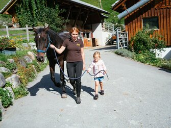 2 Mädchen führen ein Pferd über den Hof | © Urlaub am Bauernhof Vorarlberg / Daniel Gollner