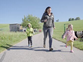 Mutter macht mit den zwei Kindern ein Wettrennen richtung Stall | © Daniel Gollner | Urlaub am Bauernhof