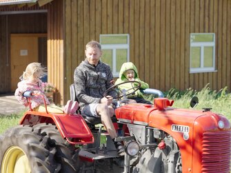 Vater fährt mit zwei Kindern auf einem oldtimer Traktor aus. | © Daniel Gollner | Urlaub am Bauernhof