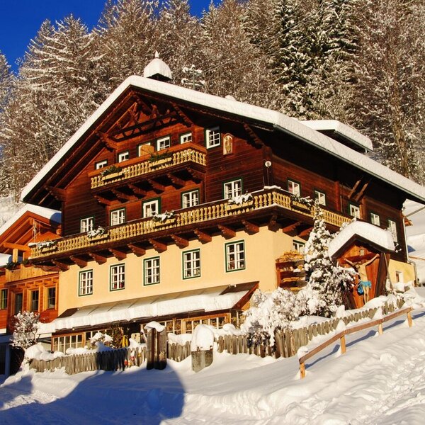 Der Bauernhof im Winter, umgeben von Schnee und Bäumen, mit Holzbalkonen und schneebedecktem Dach. Der Bauernhof im Winter, umgeben von Schnee und Bäumen, mit Holzbalkonen und schneebedecktem Dach.