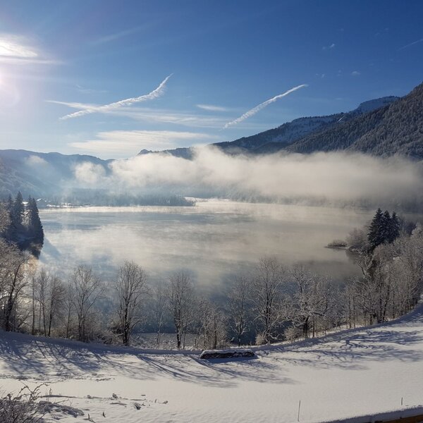 View of the misty Hintersee lake in winter, surrounded by snow-covered mountains and trees, from the Farm House. View of the misty Hintersee lake in winter, surrounded by snow-covered mountains and trees, from the Farm House.