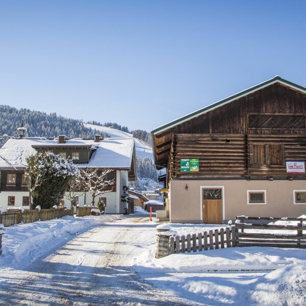 The farm house with snow-covered buildings and a winter mountain landscape in the background. The farm house with snow-covered buildings and a winter mountain landscape in the background.